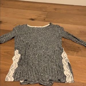 Long sleeve grey shirt with flower decor on sides.